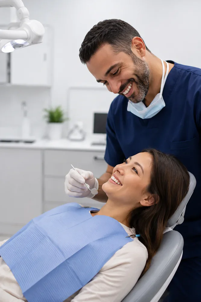 dentist smiling while examining patient